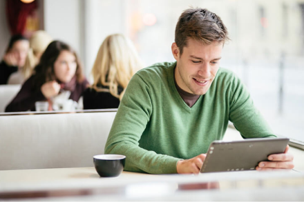 young white male using a tablet at a cafe